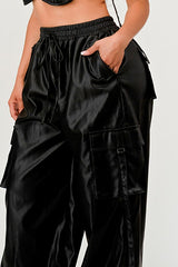 Black satin cargo pants worn by a person on a white background