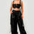 Woman wearing a black outfit with a top and wide-leg pants on a white background