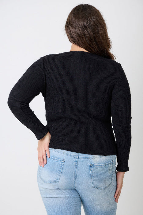 Person wearing a black sweater and light blue jeans against a white background