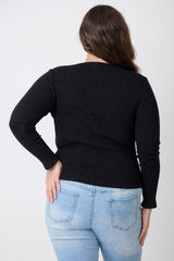 Person wearing a black sweater and light blue jeans against a white background