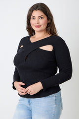 Woman wearing a black cut-out sweater and light blue jeans against a white background