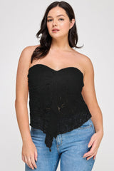 Woman wearing a black lace strapless top and blue jeans on a white background