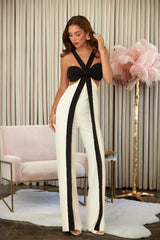 Woman wearing a black and white outfit in an elegant room with a pink chair and decorative lamp.