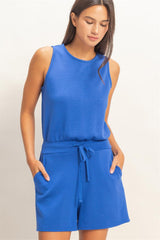 Woman wearing a blue sleeveless romper against a plain background