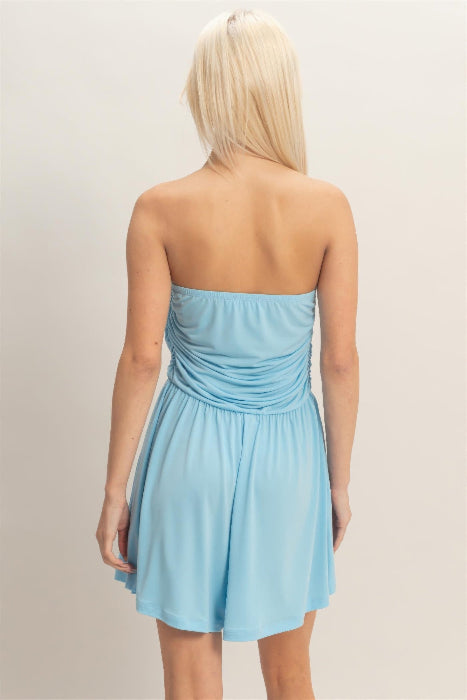 Woman wearing a light blue strapless romper  against a plain background