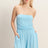 Woman wearing a light blue strapless romper against a plain background