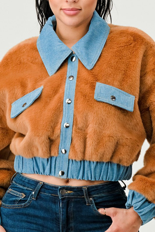 Person wearing a brown fur jacket with blue denim collar and buttons against a white background