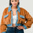 Woman wearing a brown fuzzy jacket with blue collar and jeans on a white background