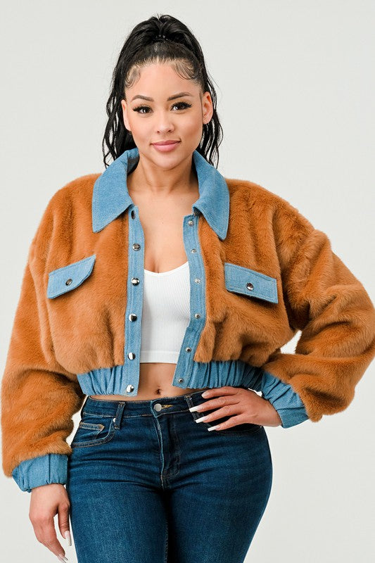 Woman wearing a brown fuzzy jacket with blue collar and jeans on a white background