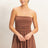Woman wearing a brown romper dress against a plain background