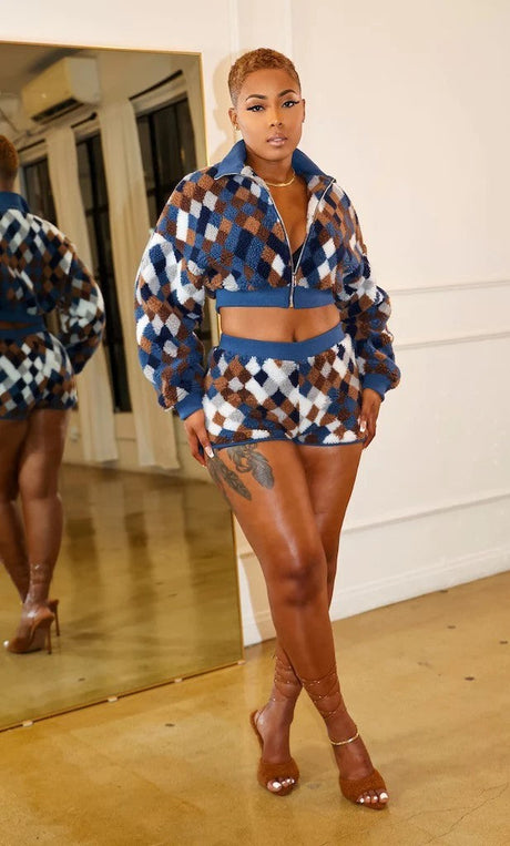 Woman in a patterned outfit standing in front of a mirror.