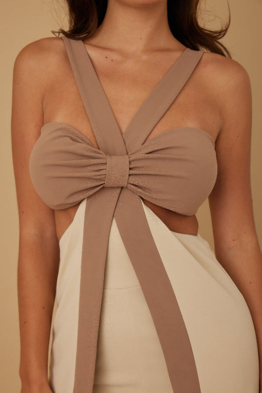 close up of Beige jumpsuit with a bow detail on a beige background