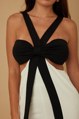close up of Black and white jumpsuit with a bow detail on a beige background