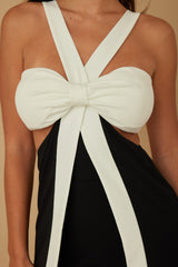 White and black jumpsuit a large bow detail on a beige background