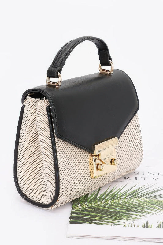 Black and beige handbag with gold accents on a white background