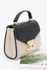 Black and beige handbag with gold accents on a white background