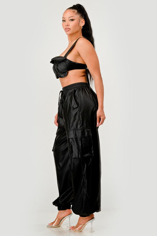 Woman wearing a black outfit with a bow top and wide-leg pants on a white background