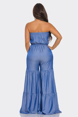 back view of Woman wearing a blue strapless jumpsuit on a white background