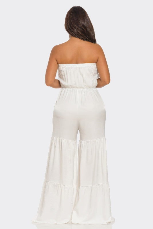 Woman wearing a white strapless jumpsuit on a white background