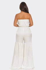 Woman wearing a white strapless jumpsuit on a white background