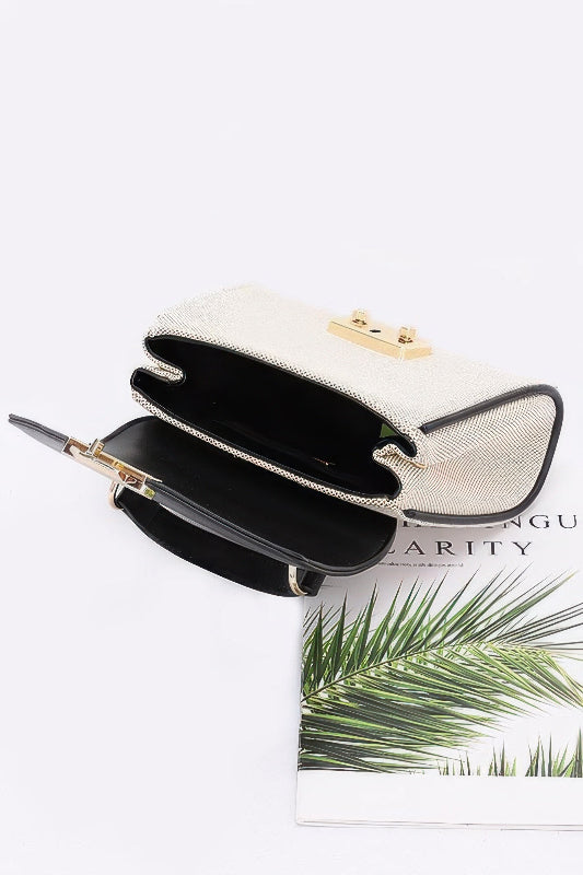 White handbag with gold accents on a magazine with green leaves