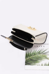 White handbag with gold accents on a magazine with green leaves