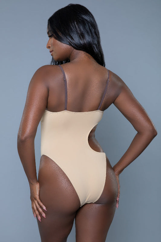Woman wearing a beige bodysuit against a gray background