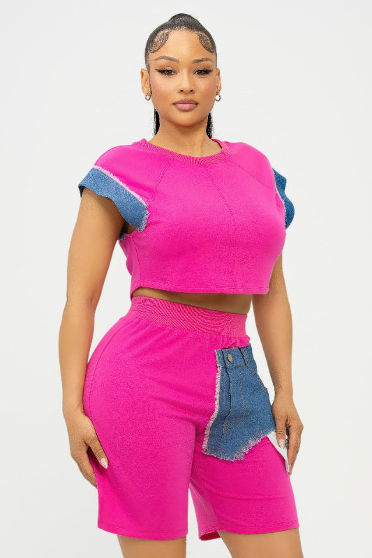 Woman wearing a bright pink short set with denim accents on a white background side view