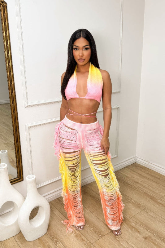 Woman wearing a colorful tie-dye outfit in a minimalistic room.