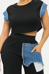 Black top with blue denim sleeves and black pants with denim pocket on a white background