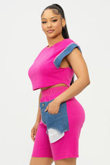 side view of a Woman wearing a bright pink outfit with denim accents on a white background