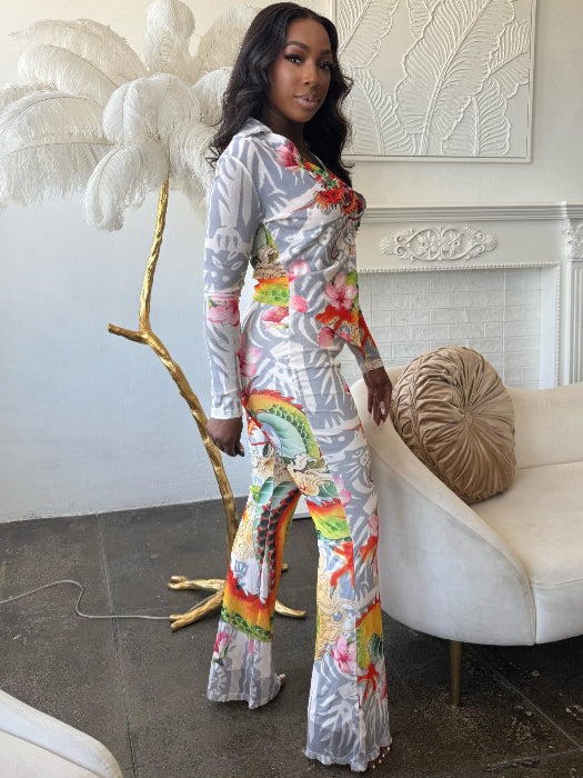 Woman in a colorful dragon print outfit standing in an elegant room with a white fireplace and decorative elements.