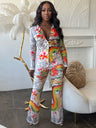Woman wearing a colorful dragon print pant set in an elegant room with decorative elements.