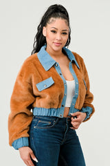 Woman wearing a brown fuzzy jacket with blue accents on a plain background