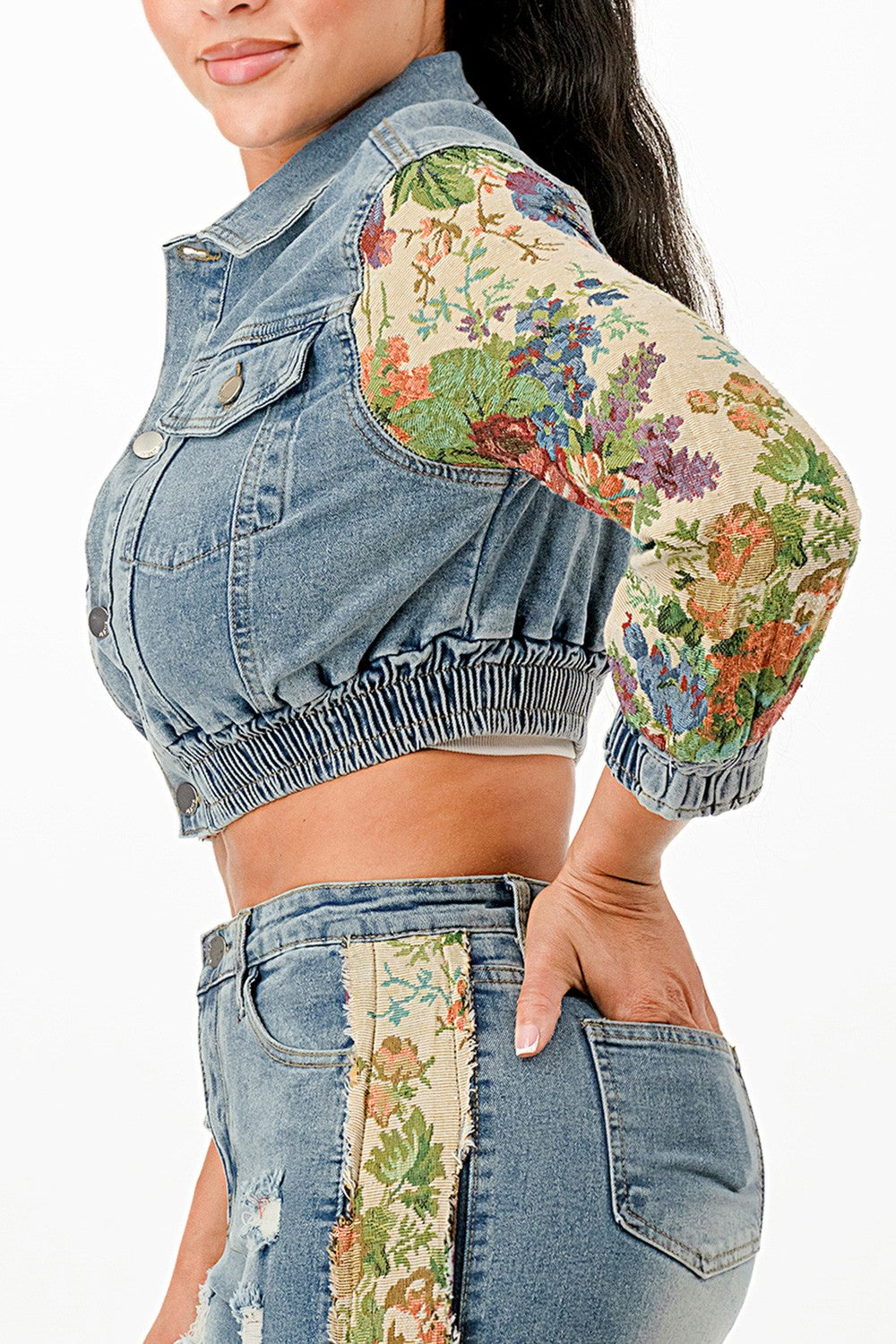 Denim jacket with floral sleeves and hem details on a white background
