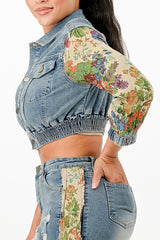 Denim jacket with floral sleeves and hem details on a white background