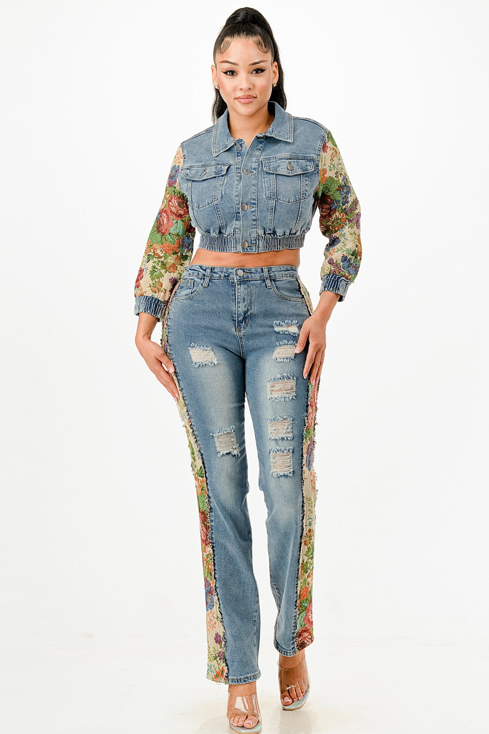 Woman wearing a denim jacket and jeans with floral sleeves on a white background