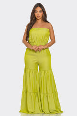 Woman wearing a bright green strapless jumpsuit on a white background