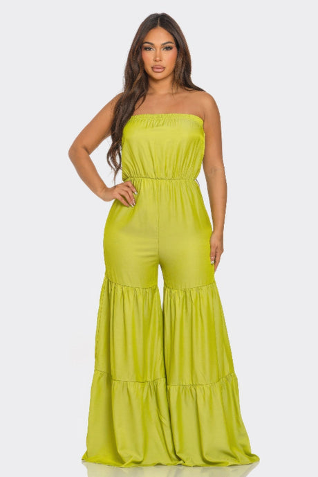 Woman wearing a bright green strapless jumpsuit on a white background