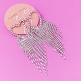 Sparkly tassel earrings on a pink background with 'Ellison + Young' card.