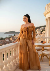 Woman in a mustard yellow outfit standing on a balcony with a scenic view.