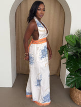 Woman wearing a patterned jumpsuit standing in a room with a plant.