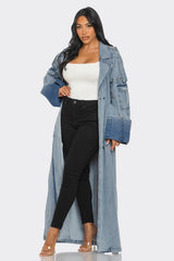 Woman wearing a long denim jacket over a white top and black pants on a white background