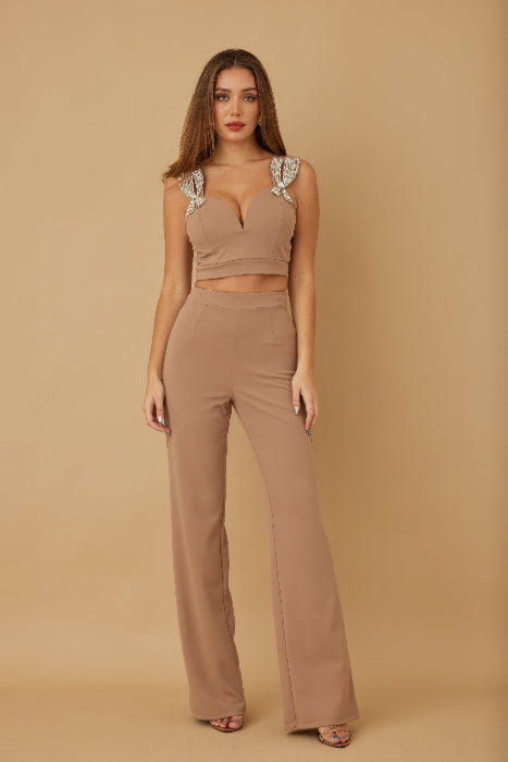 Woman wearing a beige outfit with jewel embellishments on a beige background