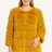 Woman wearing a mustard yellow fur coat on a white background