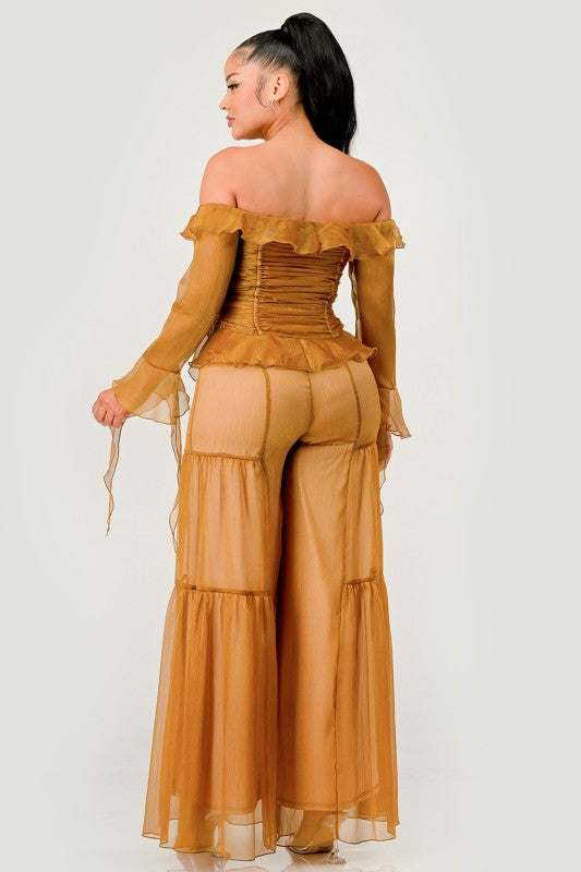 Woman wearing a mustard yellow off-shoulder top and wide-leg pants on a white background