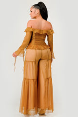 Woman wearing a mustard yellow off-shoulder top and wide-leg pants on a white background