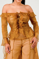 Woman wearing a mustard yellow off-shoulder top and pants on a white background