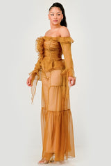 Woman wearing a mustard yellow off-shoulder dress with ruffled details on a white background