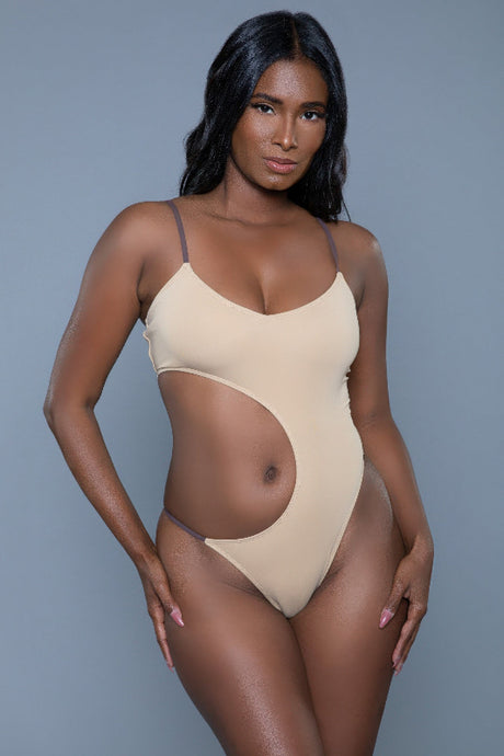 Woman wearing a beige bodysuit against a gray background